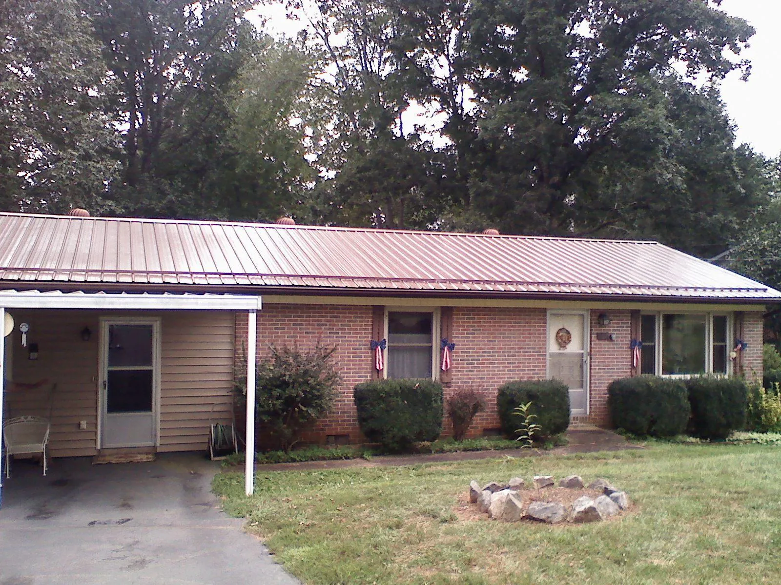 Bronze metal roof and carport on a brick ranch home — Roof Repair work by our crew in Peru