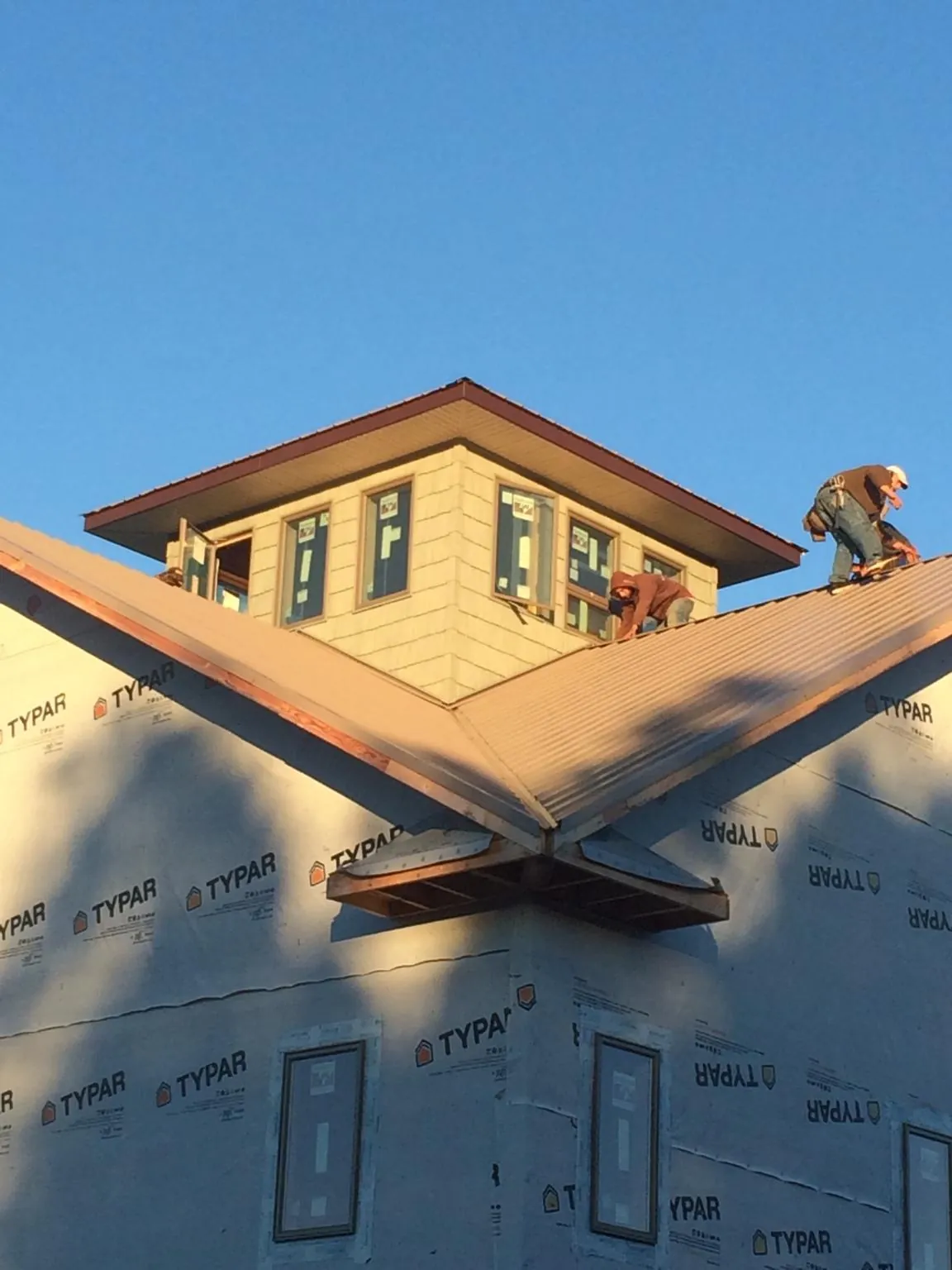 Roofers working around a rooftop cupola on a new metal roof at sunset — Roof Waterproofing in Peru by Roofing Brothers